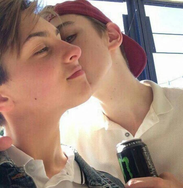 One teen boy kissing another on the cheek