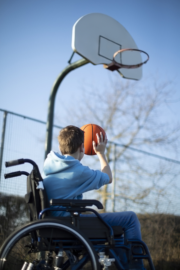 Teenage boy in wheelchair shooting for goal