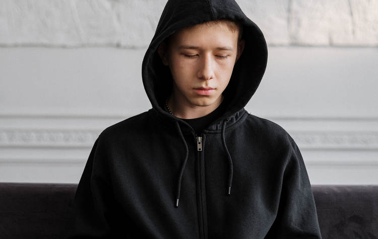 Depressed teenage boy in black hoodie