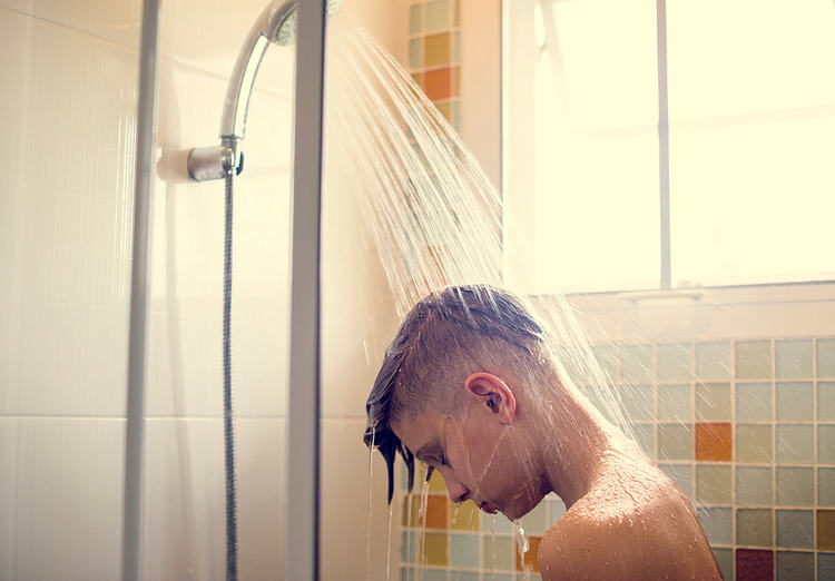 Head and shoulders of teenage boy in shower