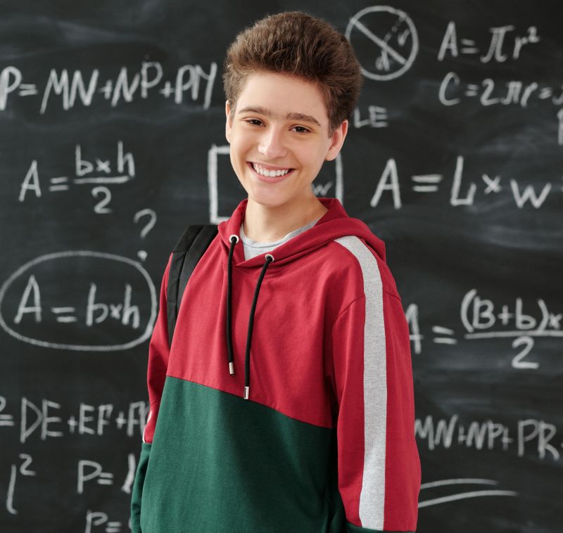 Teenage boy standing in front of blackboard