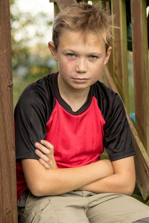 Sad pre-teen boy sitting on climbing frame