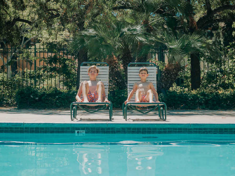 Two boys relaxing in pool lounge chairs