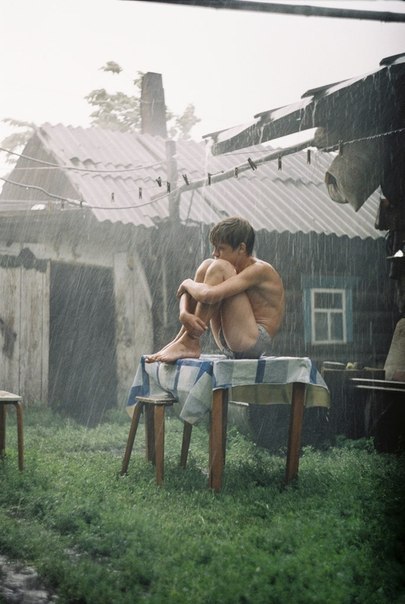 Boy sitting on a table in the rain