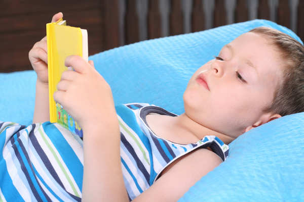 Young boy lying on bed reading