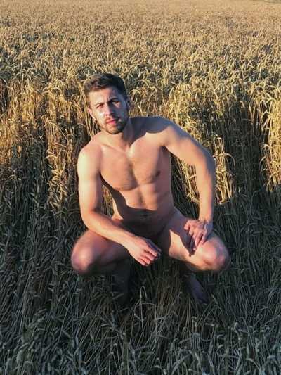 Naked man sitting on his haunches in a crop