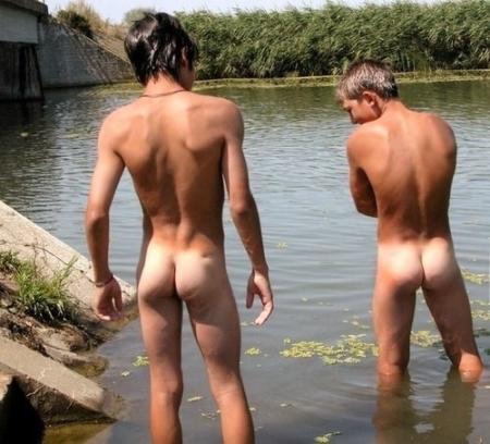 Two naked young men standing in river