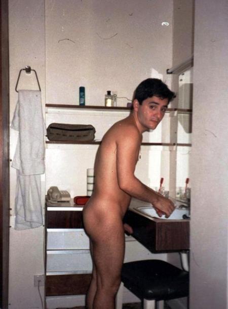 Young naked man standing at bathroom sink