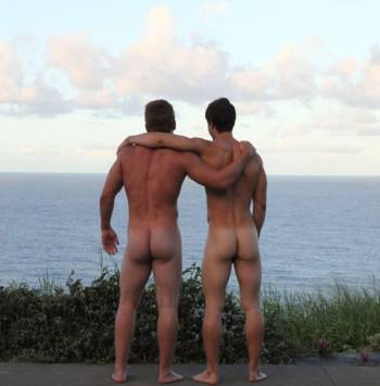 View from behind of two naked young men looking out over lake