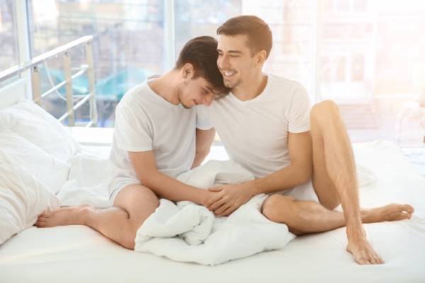 Two young men sitting on bed