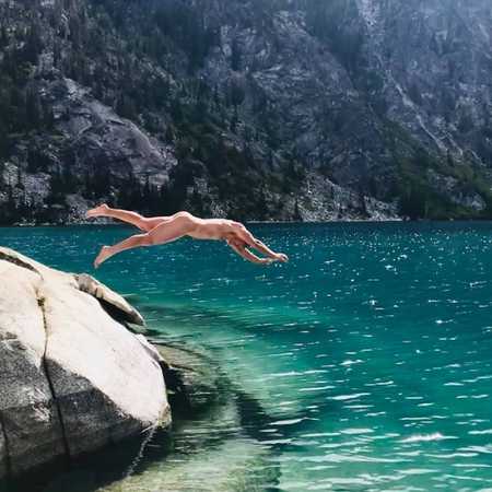 Nude man diving off rock