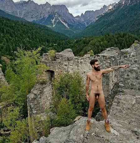 Nude man standing on edge of rocky cliff