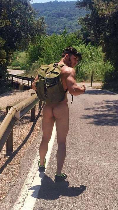 Nude man hiking along a road