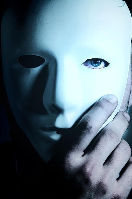 Hand holding a mask over a face, with one blue eye showing