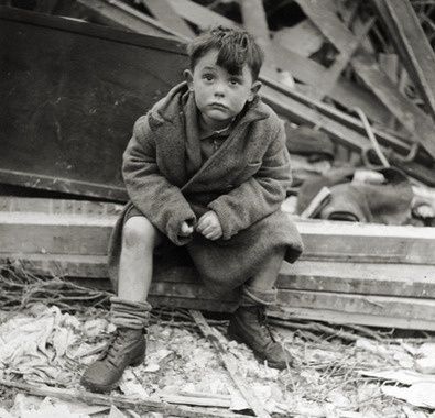 Sad young boy sitting on a plank amidst destruction