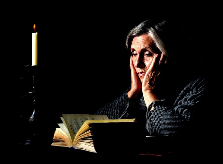 Portrait of a senior woman with book and candle