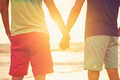 Two youn men holding hands watching sunset